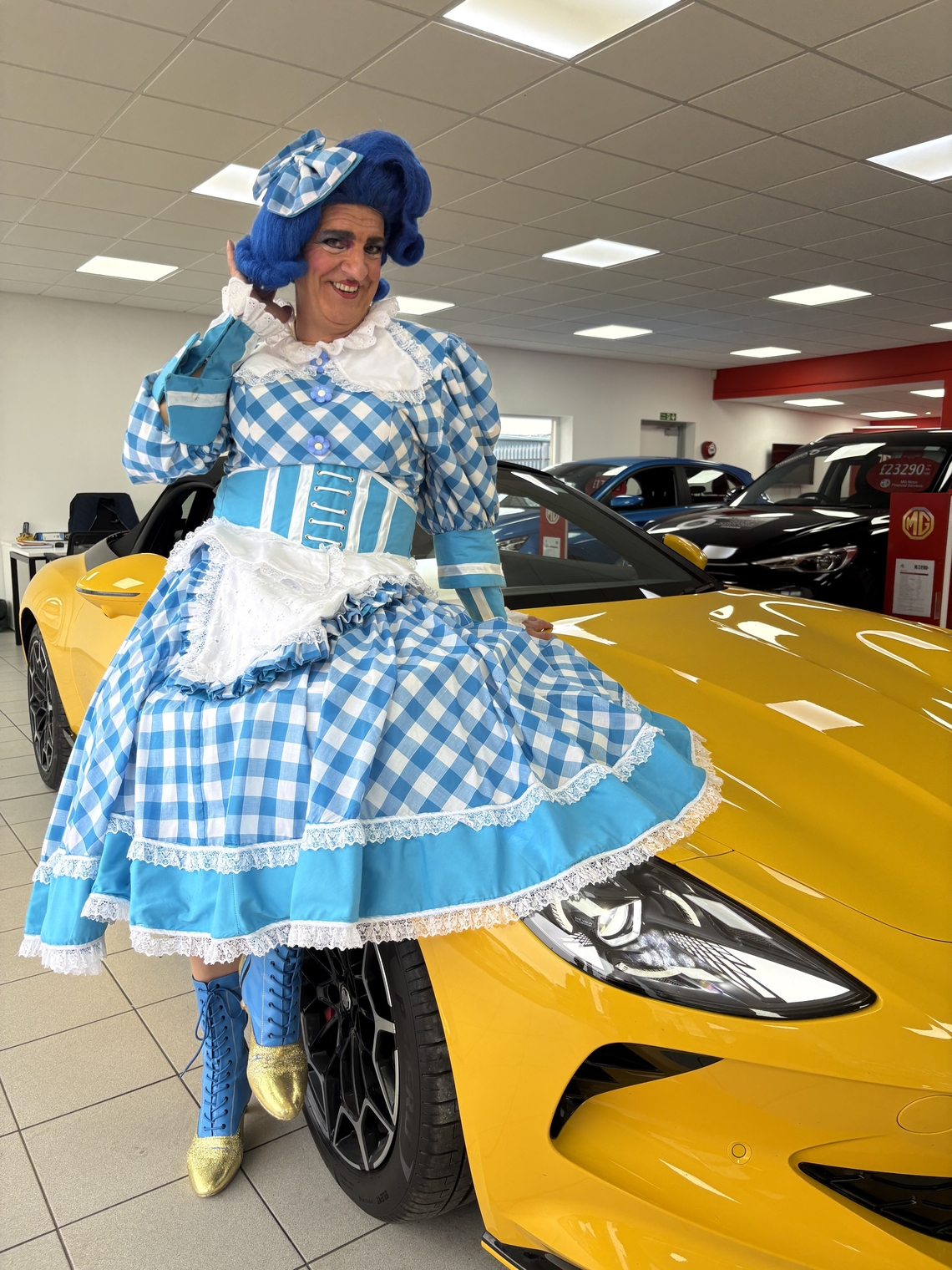 Dame Moira sits on a yellow car at Dicksons