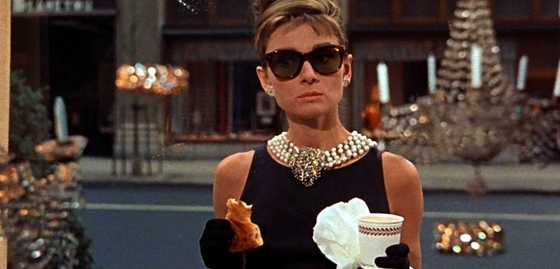 Picture of a lady holding a croissant and a coffee cup in her hands